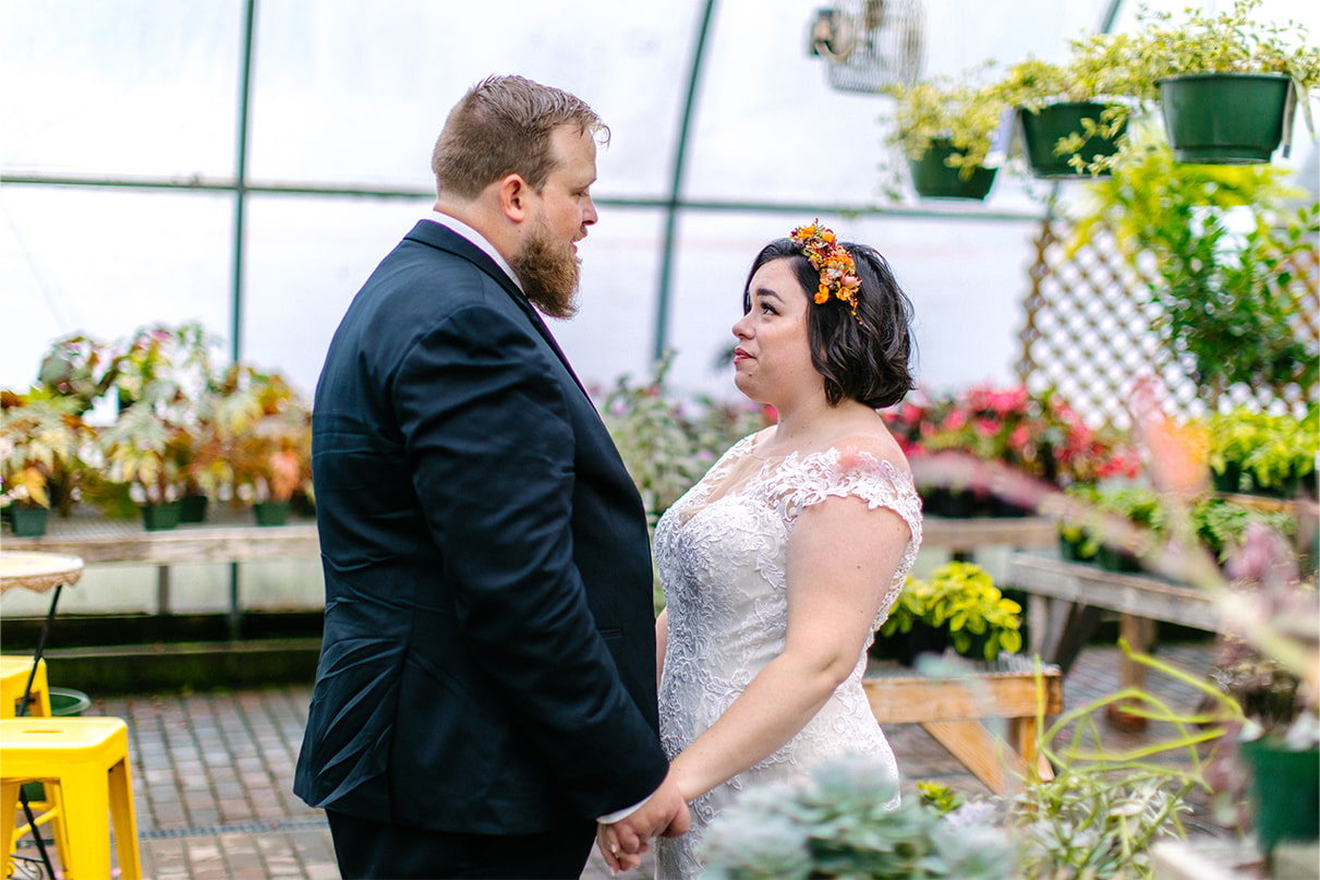 Bride and groom hold hands looking at each other at Carol Watson Greenhouse in Lafayette NY