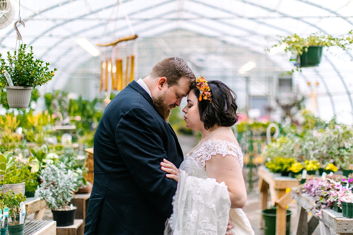 Bride and groom stand with foreheads together at Carol Watson Greenhouse in Lafayette NY