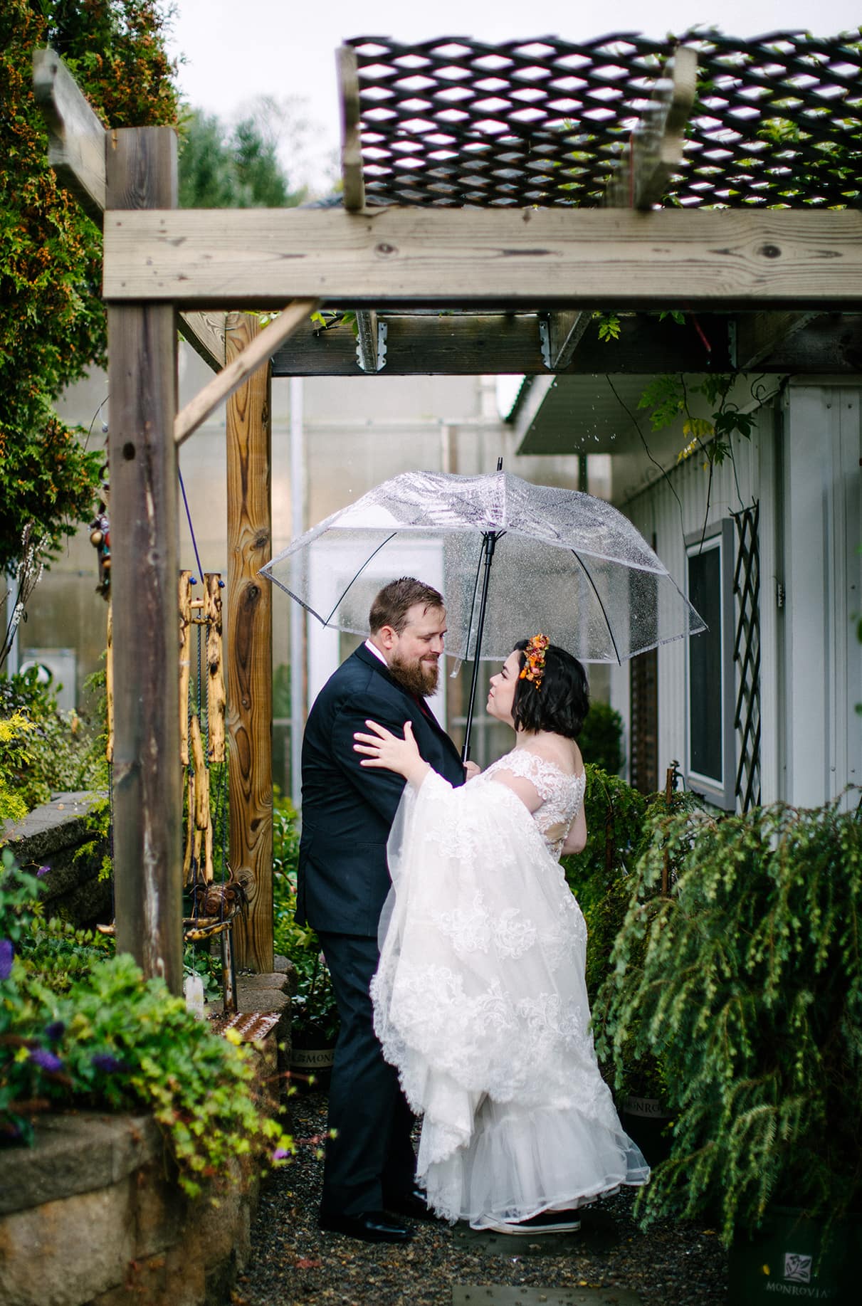 Bride and Groom stand under clear umbrella at Carol Watson Greenhouse in Lafayette NY