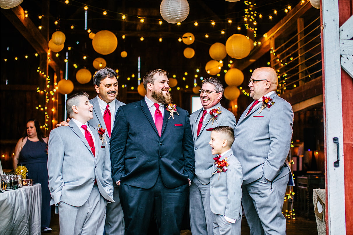 Groom and groomsmen smile and laugh inside of barn at Arlington Acres in Lafayette NY