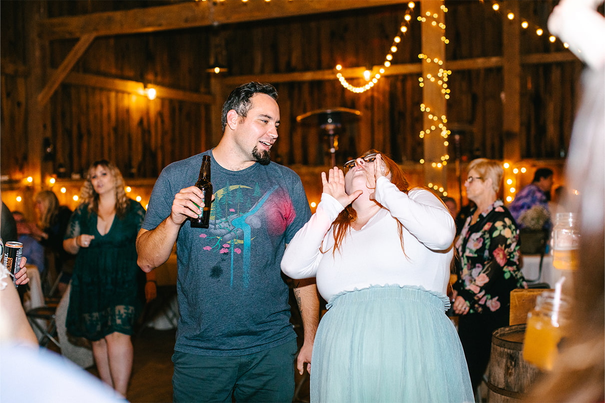 Guests drink beer and sing during wedding reception in barn at Arlington Acres in Lafayette NY