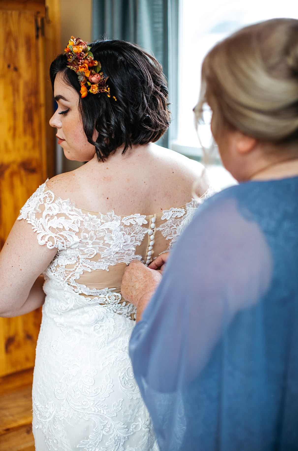 Mom zips up the back of bride's dress