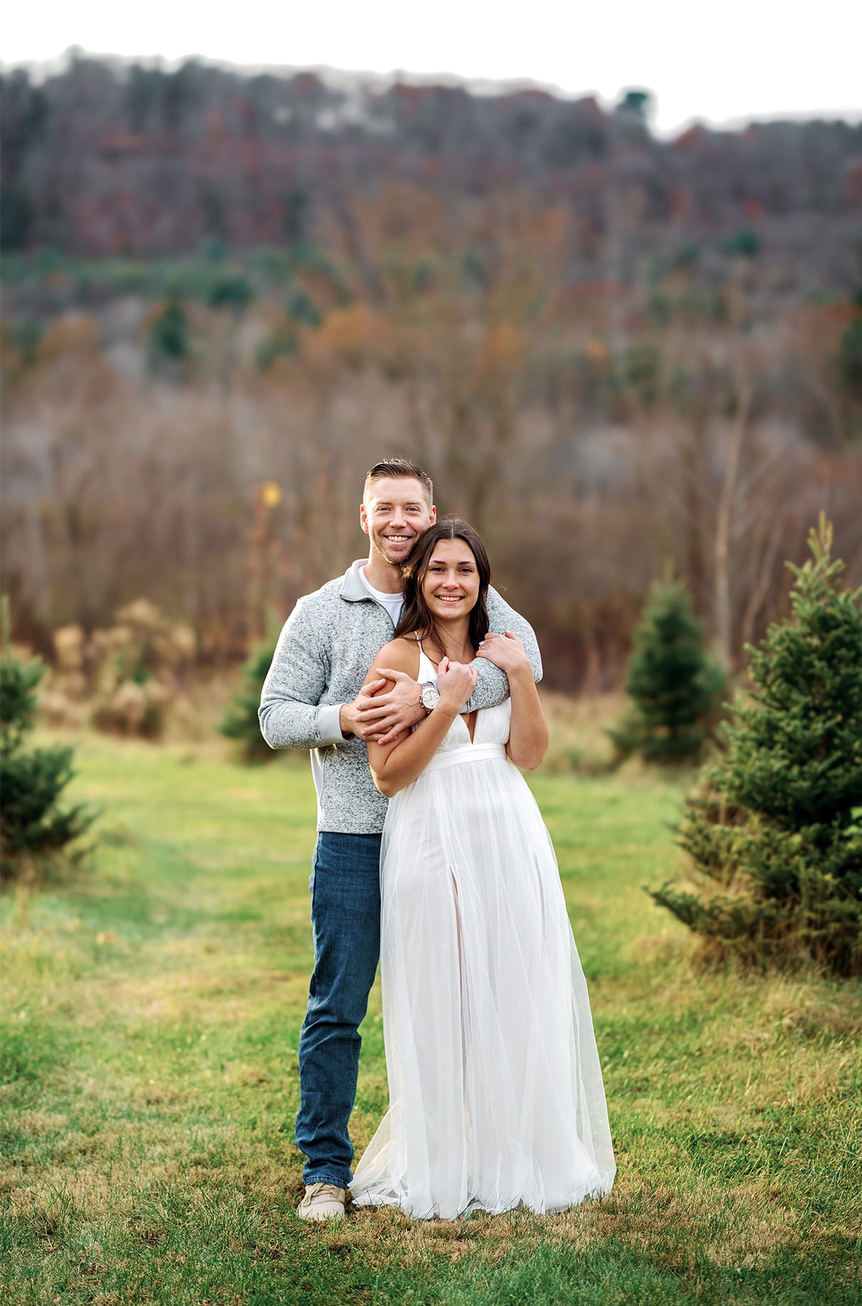 Couple stands together in Christmas tree farm field at at Sipples Farm in Bainbridge NY