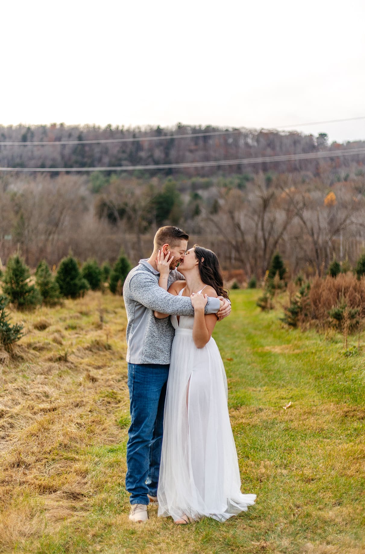 Engaged couple embraces and almost kisses in christmas tree farm field at Sipples Farm in Bainbridge NY