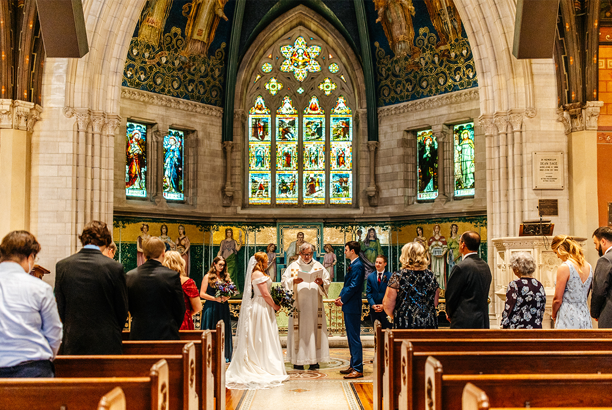 Bride and groom stand at the altar of intricate catholic church
