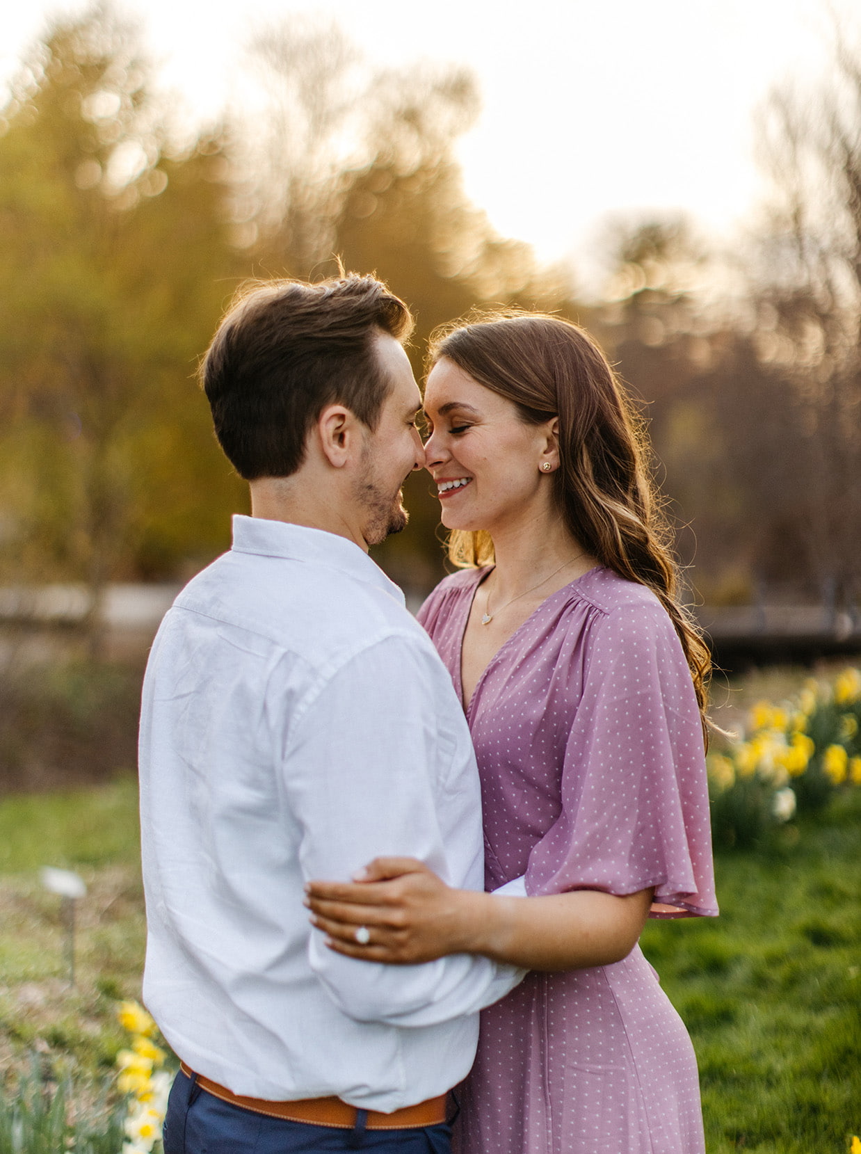 Couple smiles and almost kisses during golden-hour garden engagement session