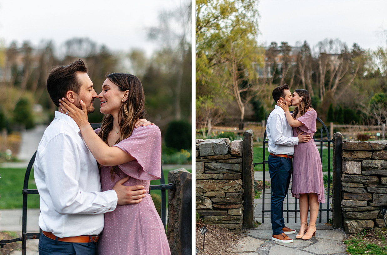 Couple stands together and kisses in front of garden gate at the Cornell Botanic Gardens