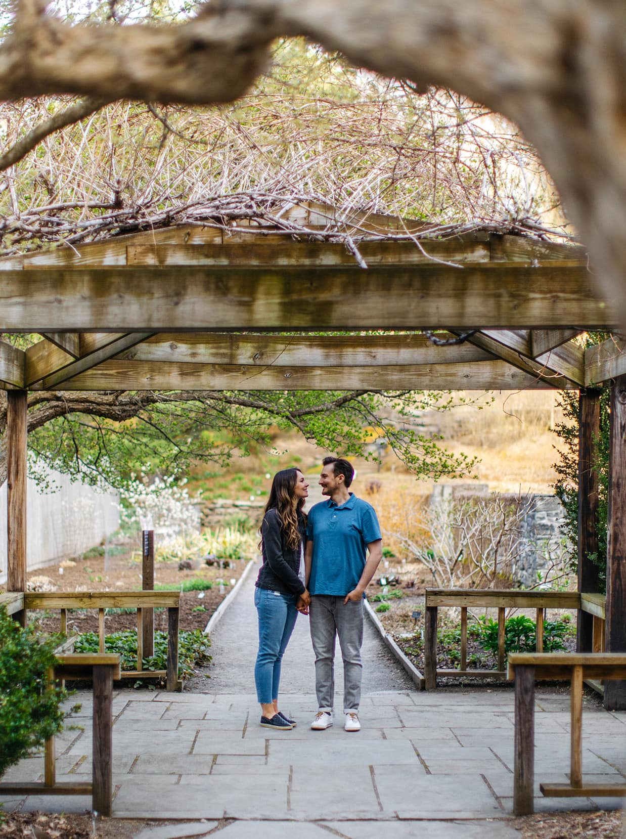 Couple standing together under arbor during engagement session