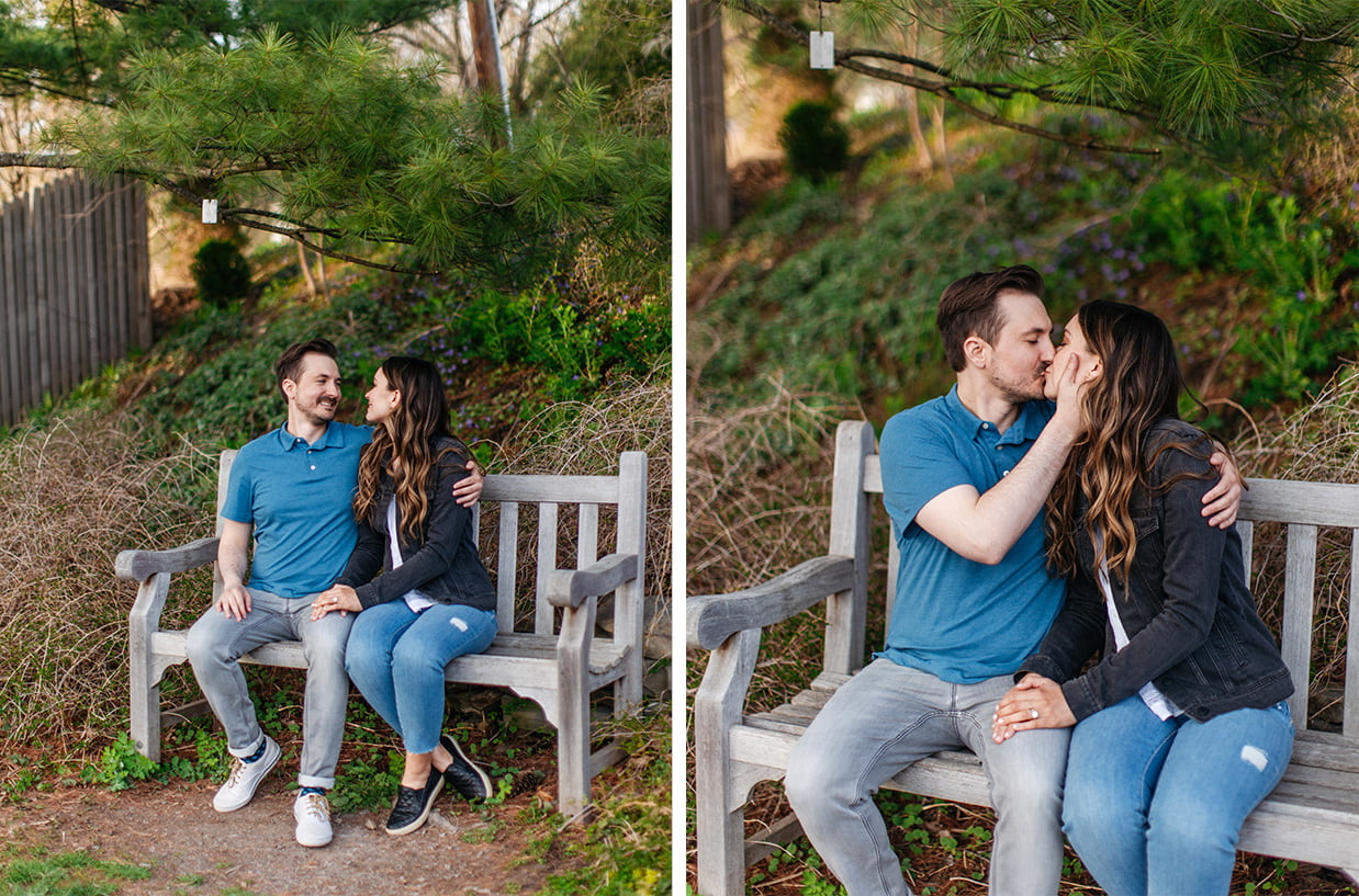 Couple in jeans, a blue polo, and black jean jacket sitting on a bench for engagement photos