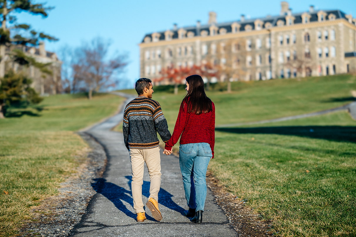 Couple holds hands and walks up path at Cornell University in Ithaca, NY