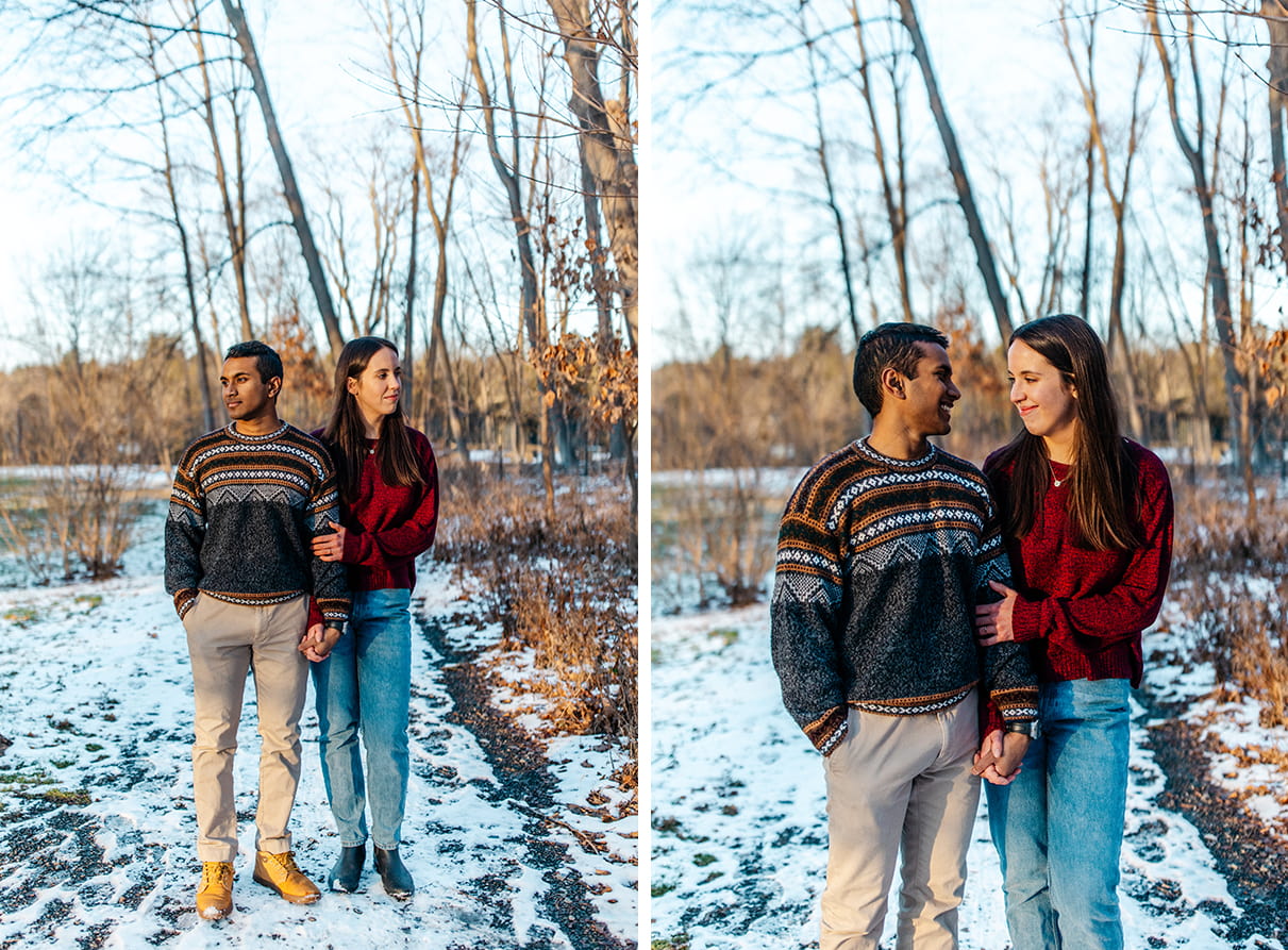 Couple looks at each other and smiles while holding hands on a wooded, snowy path during engagement session on Cornell University Campus in Ithaca, NY 