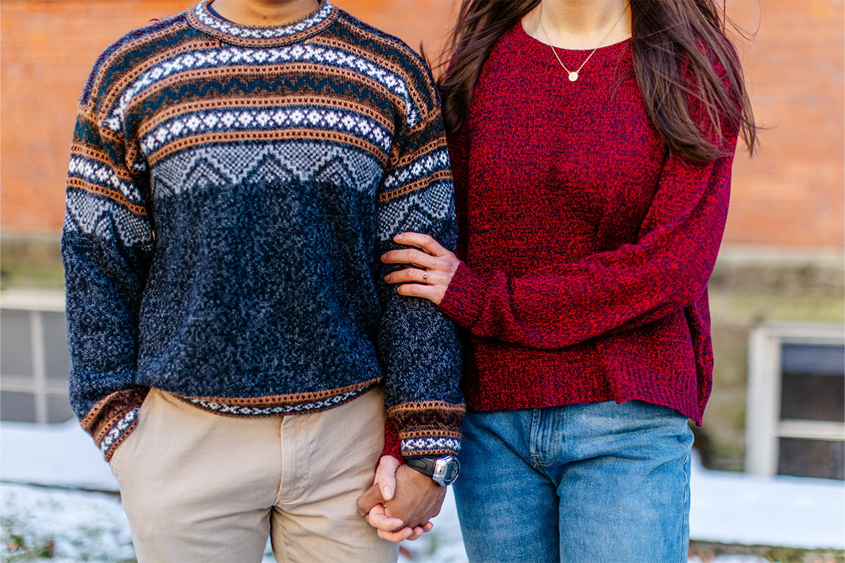 Couple wearing sweaters holds hands