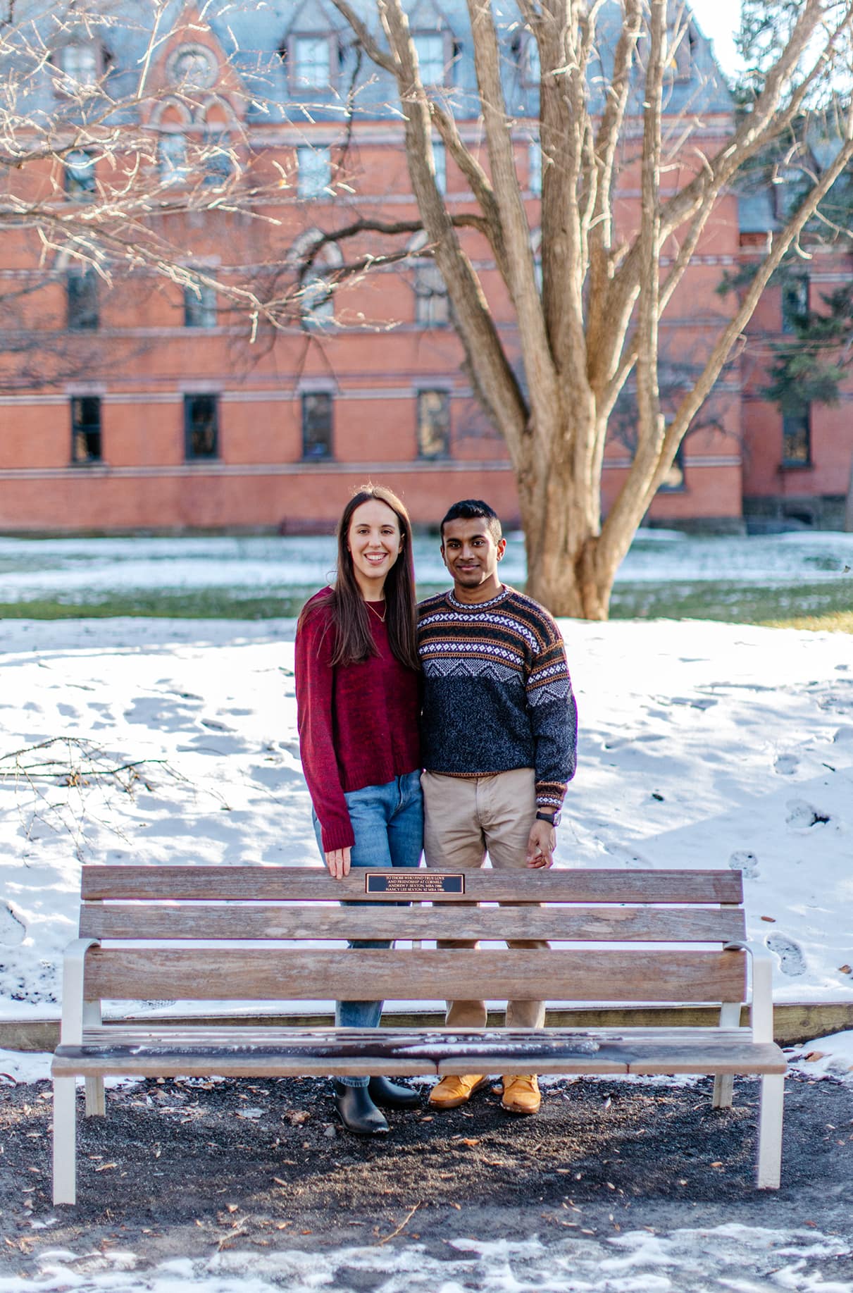 Couple standing in front of bench dedicated to students who have found love on the Cornell University Campus in Ithaca, NY