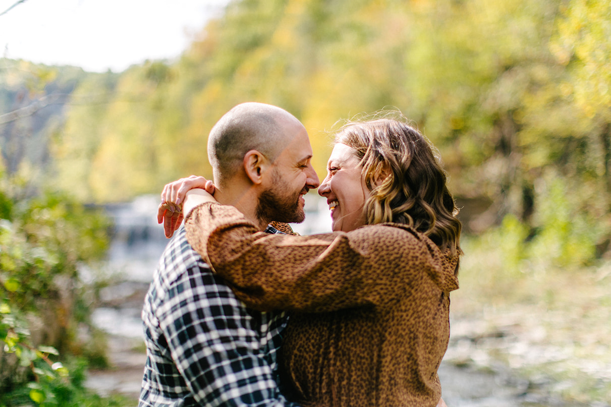 Couple laughs and embraces in front of lower falls at Taughannock Falls State Park in Trumansburg, NY