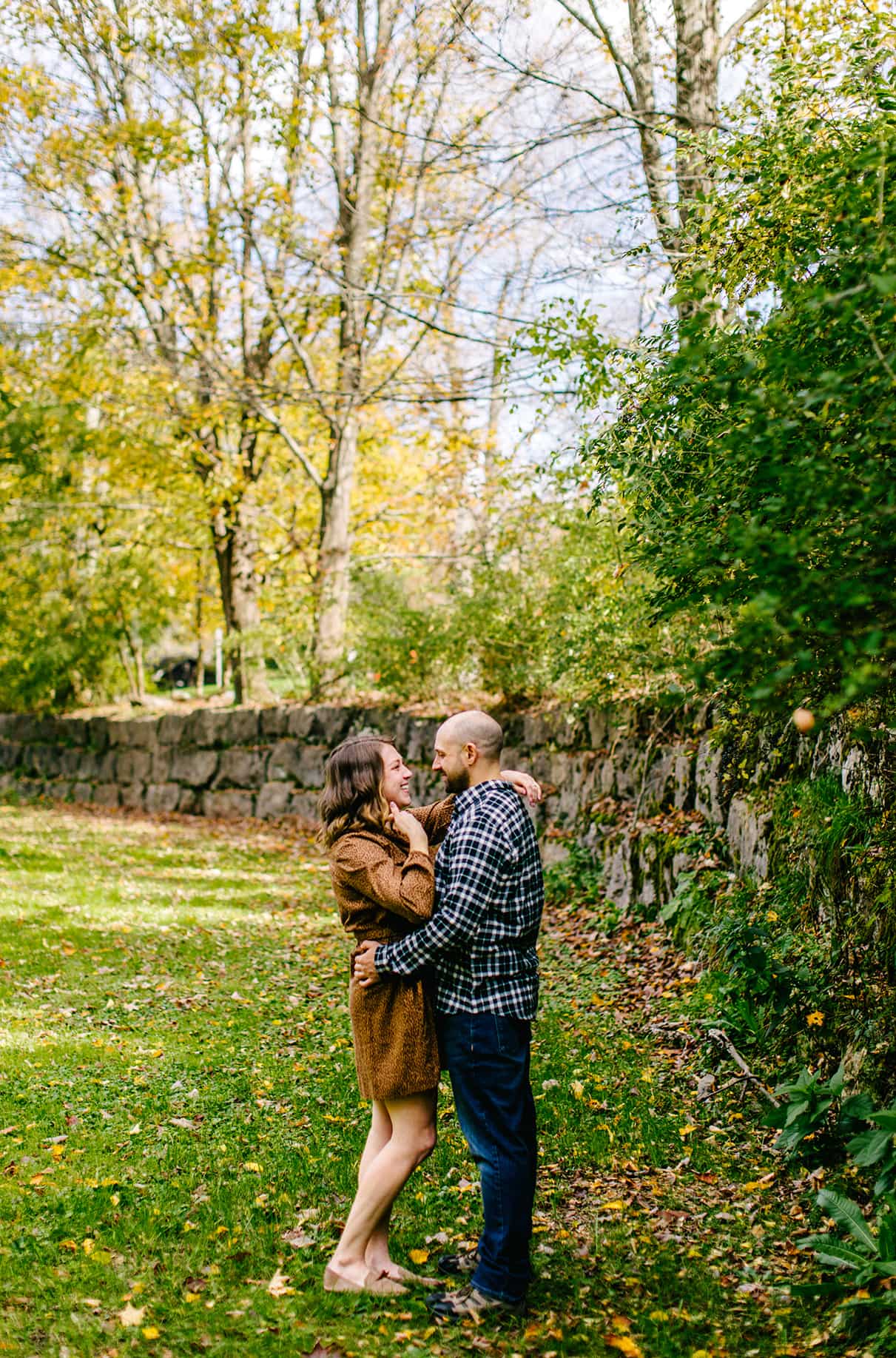 Couple embraces in front of stone wall at Taughannock Falls State Park in Trumansburg, NY