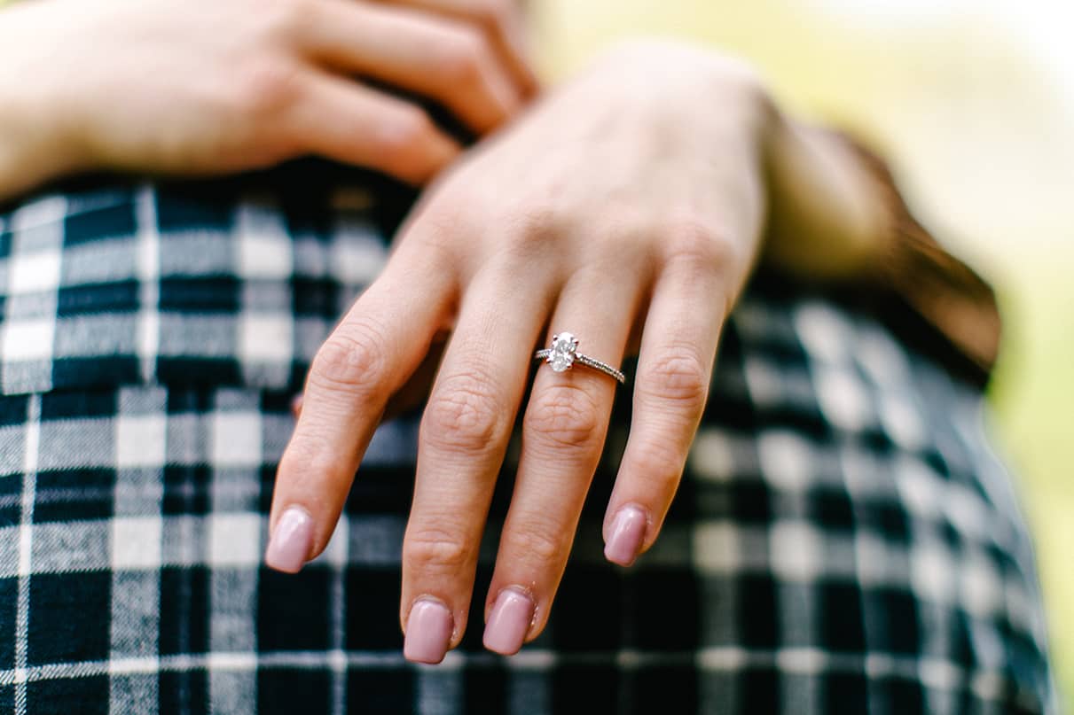 Up close shot of engagement ring on hand resting on partner's shoulder