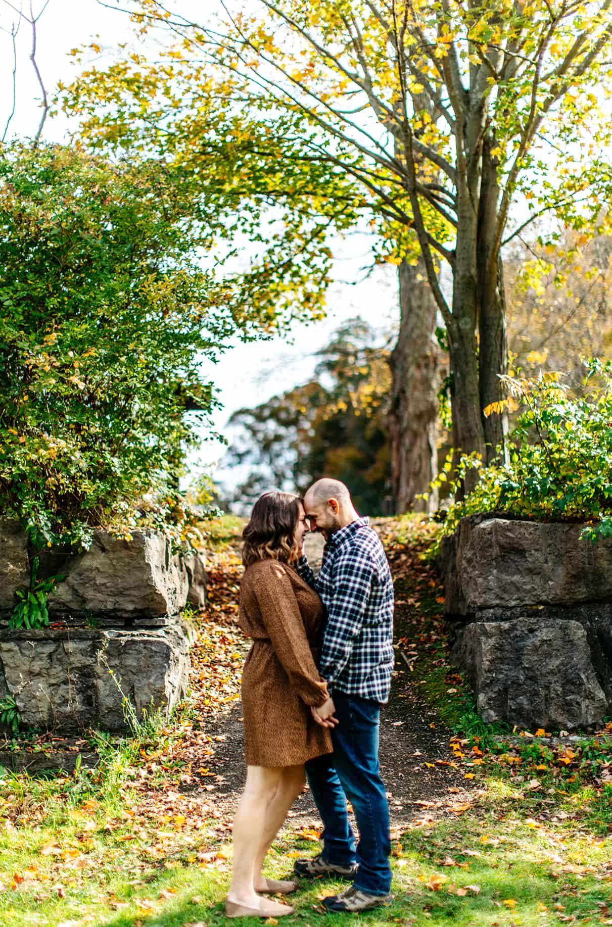 Couple holding hands and embracing in front of stone wall