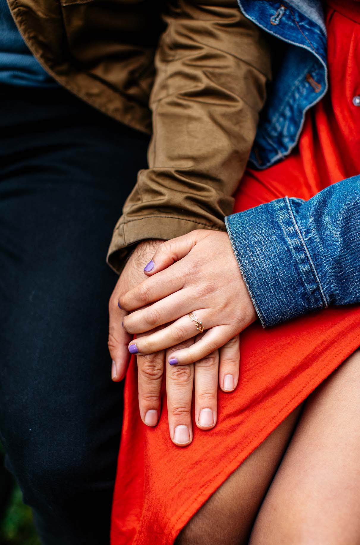 Man and womans hands rest on woman's leg, showing off her engagement ring