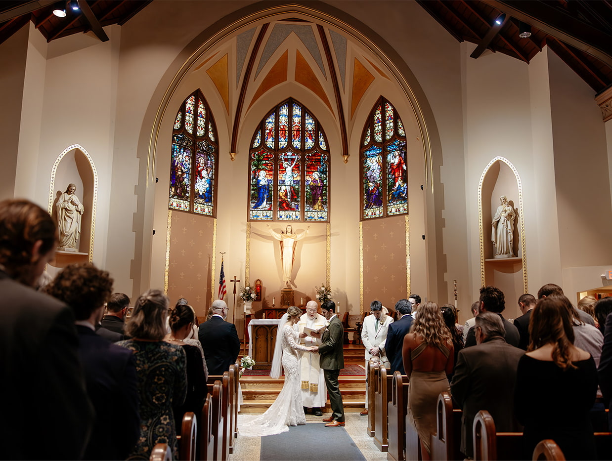 bride and groom hold hands during wedding ceremony in Skaneateles church