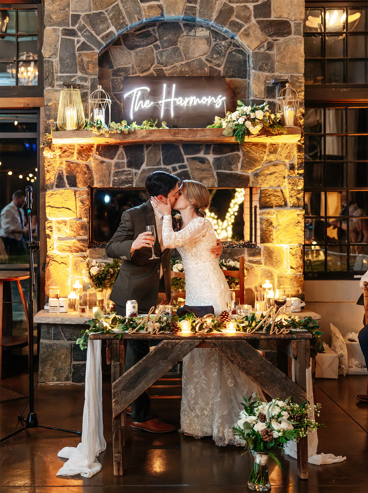 Bride and groom share a kiss in front of the fireplace at The Sinclair of Skaneateles in Skaneateles NY