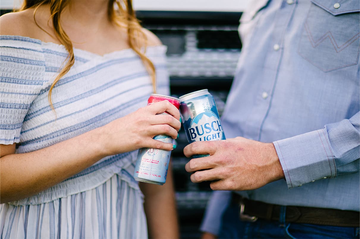 Hands holding can of Bush light and other beverage