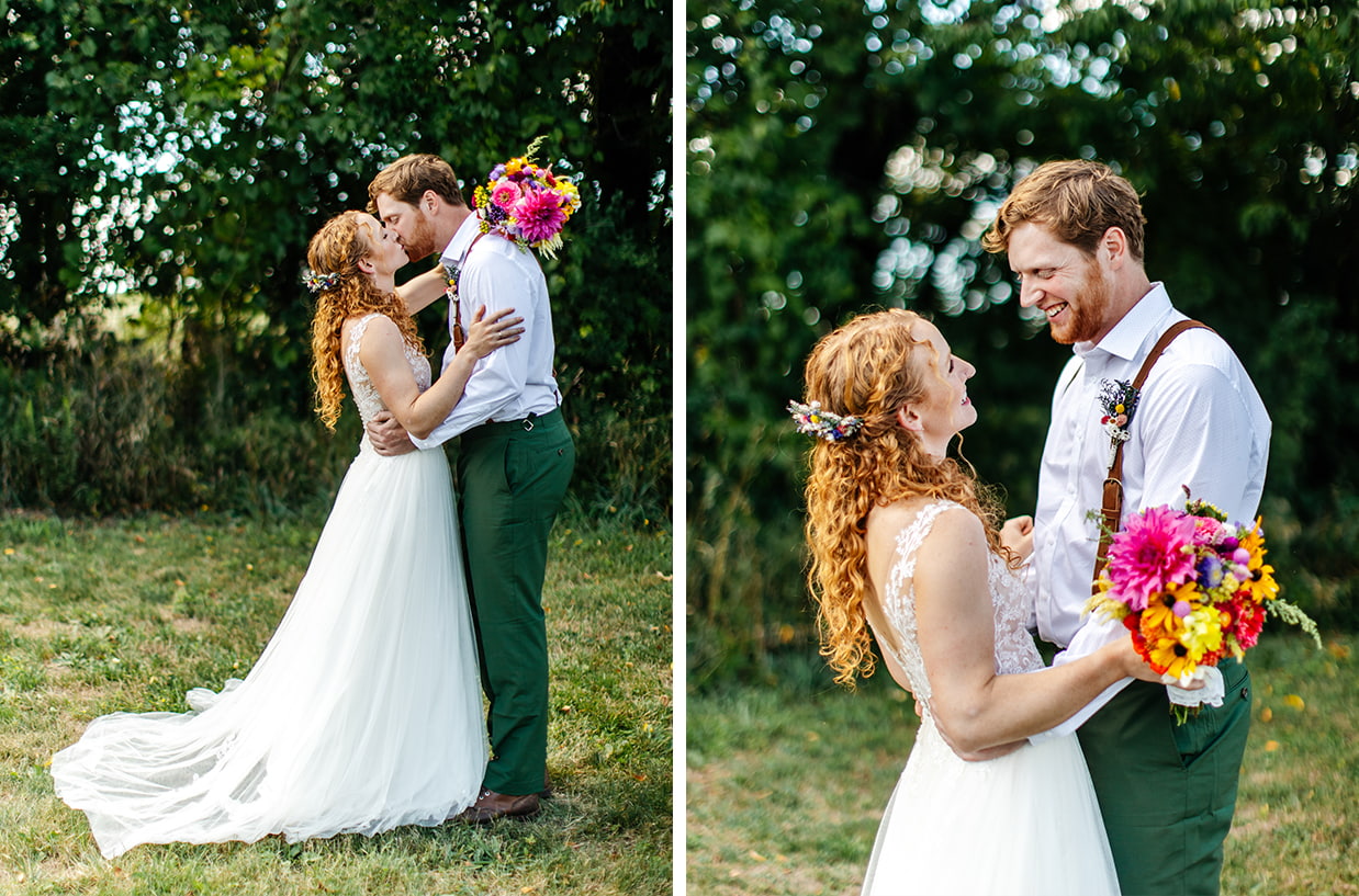 groom and bride holding colorful bouquet share a kiss in front of lush greenery