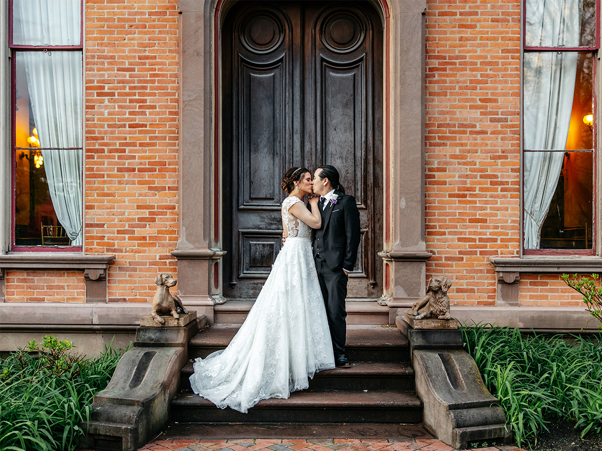 bride and groom kiss on staircase outside of canfield casino in saratoga springs ny
