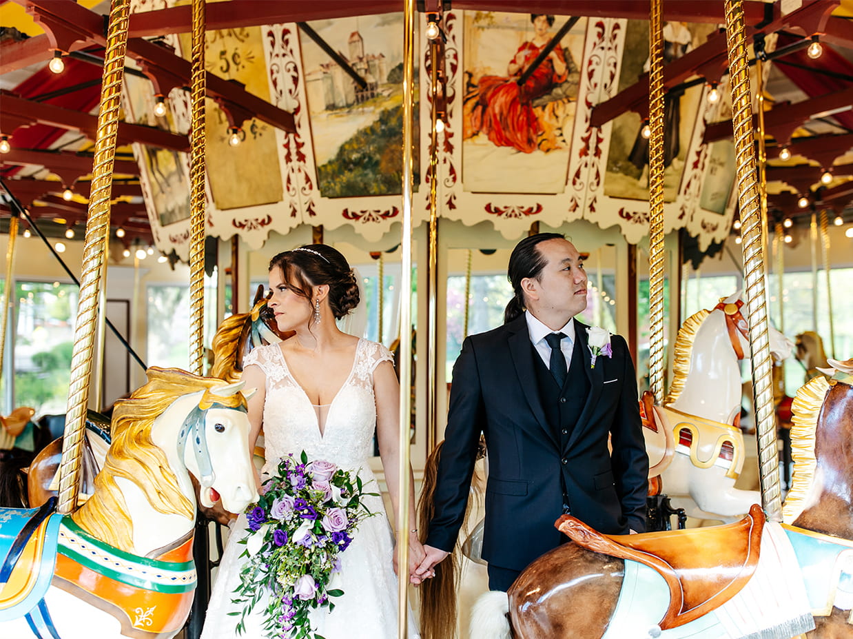 Bride and groom pose for colorful wedding photo in the Congress Park Carousel in Saratoga Springs NY