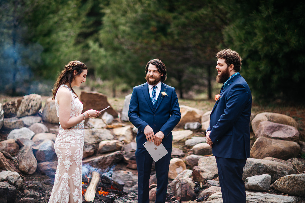 bride and groom read vows in front of fire in adirondacks