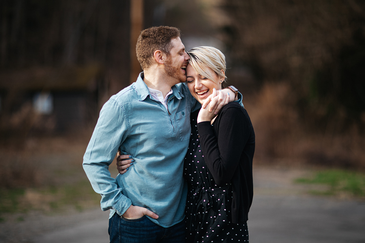 Couple laughs and embraces during engagement photos at Buttermilk Falls in Ithaca NY