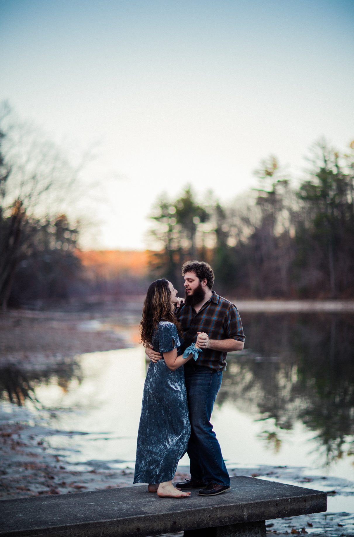 Couple dances barefoot on dock during sunset engagement session