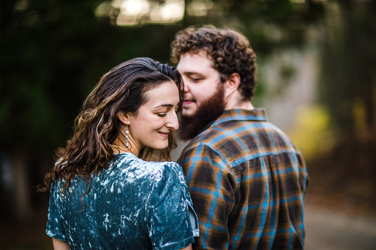 Woman in velvet dress looks down at shoulder during engagement session at Chenango Valley State Park