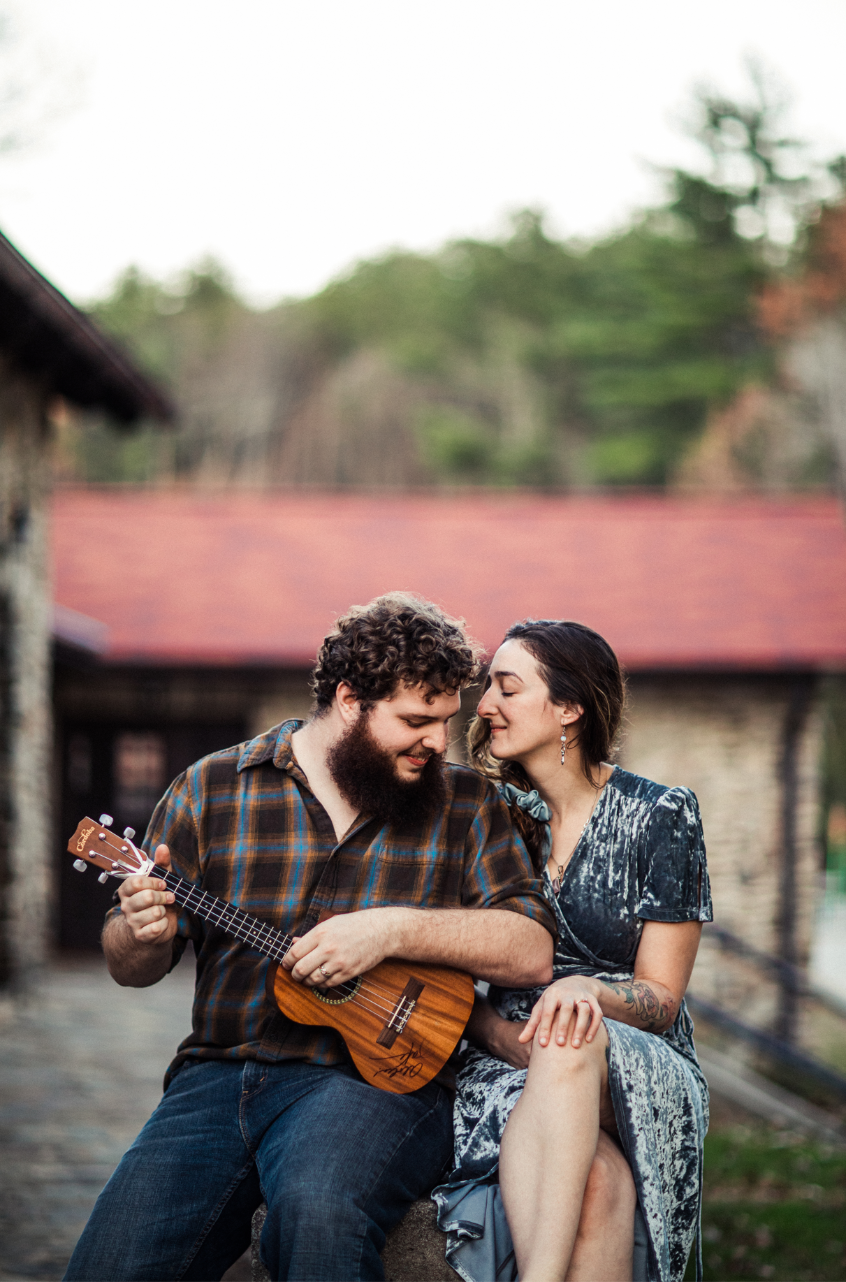 Woman listens while man plays ukulele next to her during engagement session