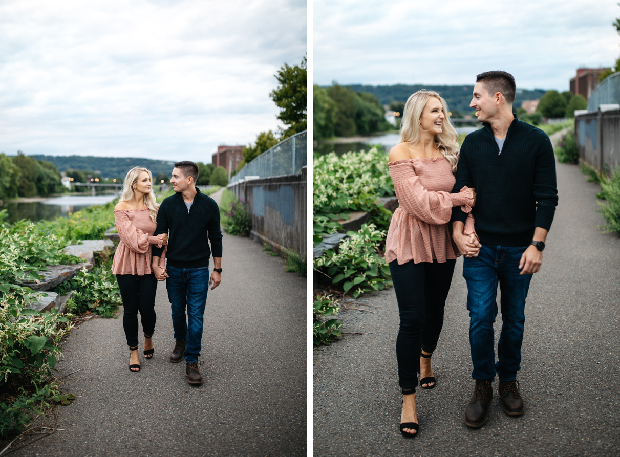 Couple holds hands and walks down path along river Binghamton NY