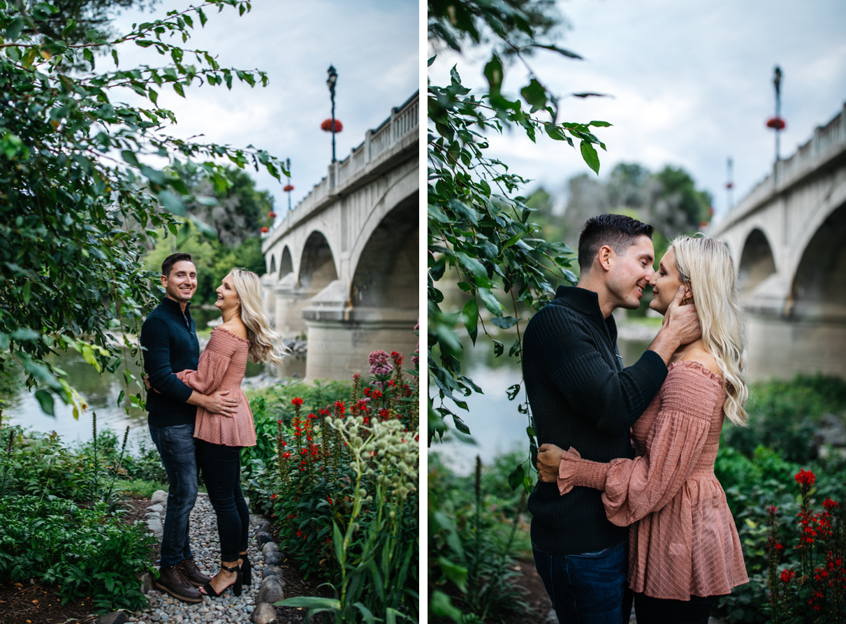 Couple laughs and embraces in front of river on garden path engagement photos