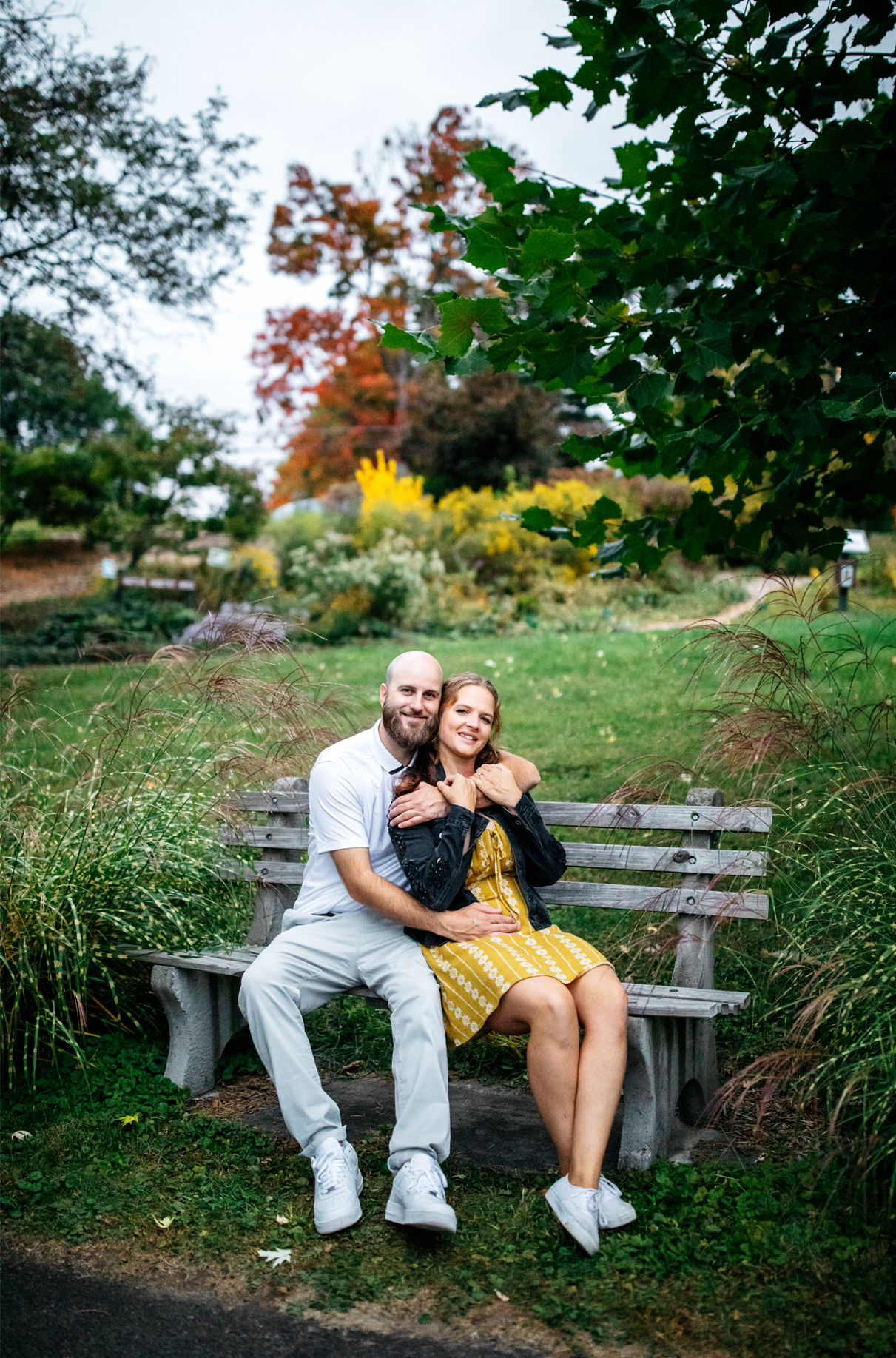 couple smiles while sitting on bench in Cutler botanic garden