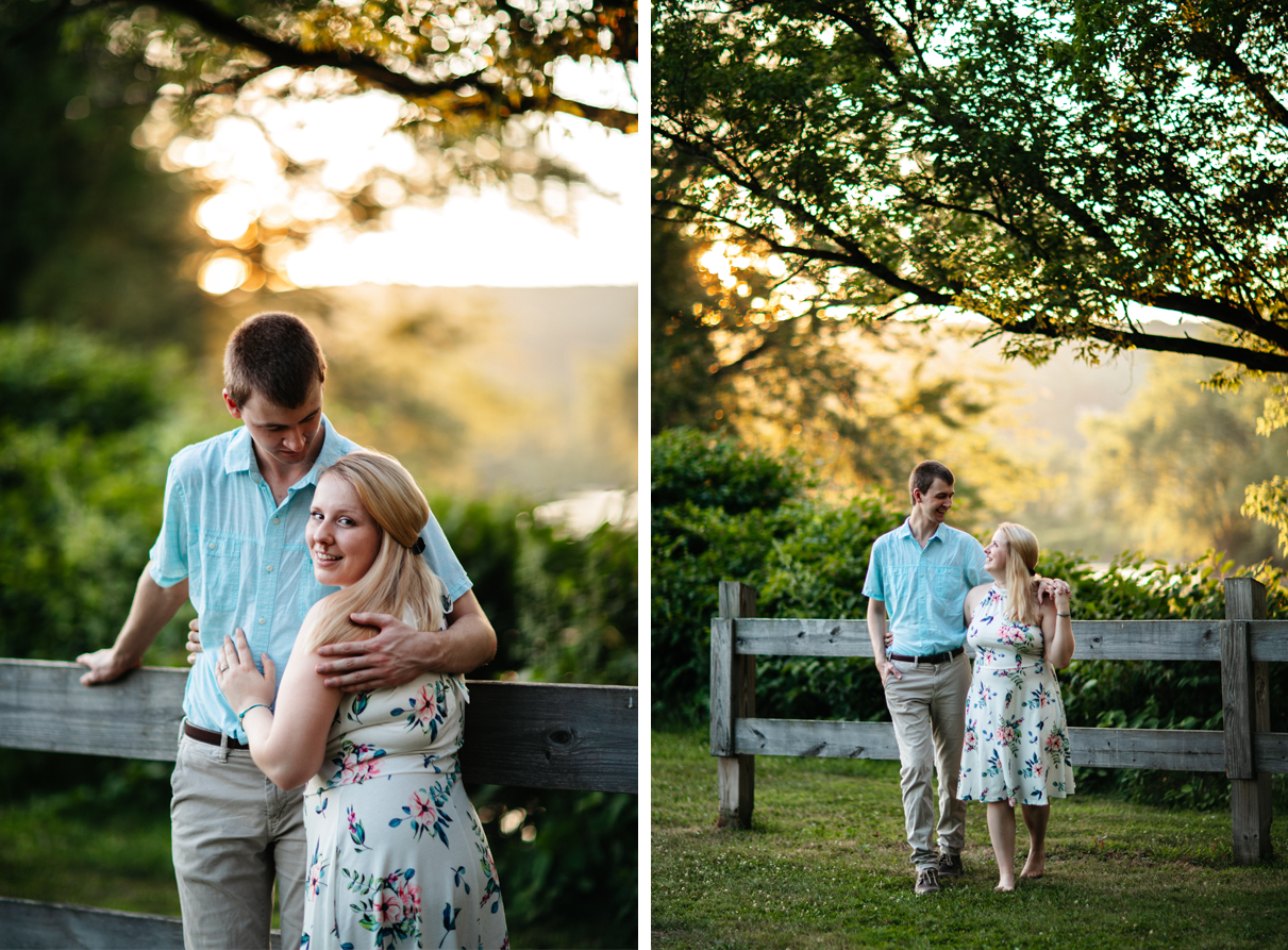 Couple embraces and walks in front of fence during sunset