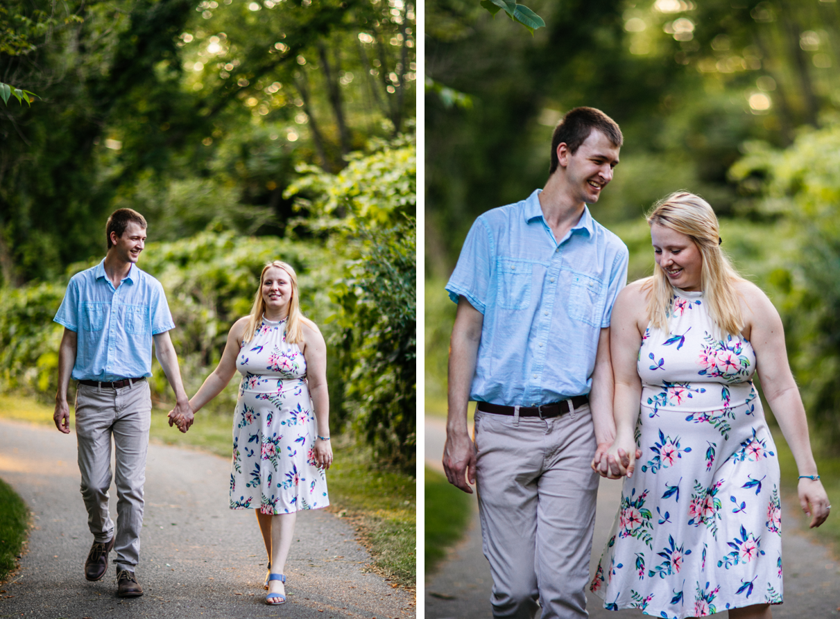 Couple smiles and holds hands as they walk along park path