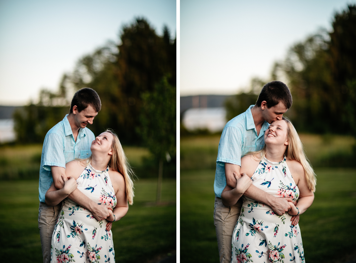 Man hugs woman from behind and kisses her forehead in park engagement session