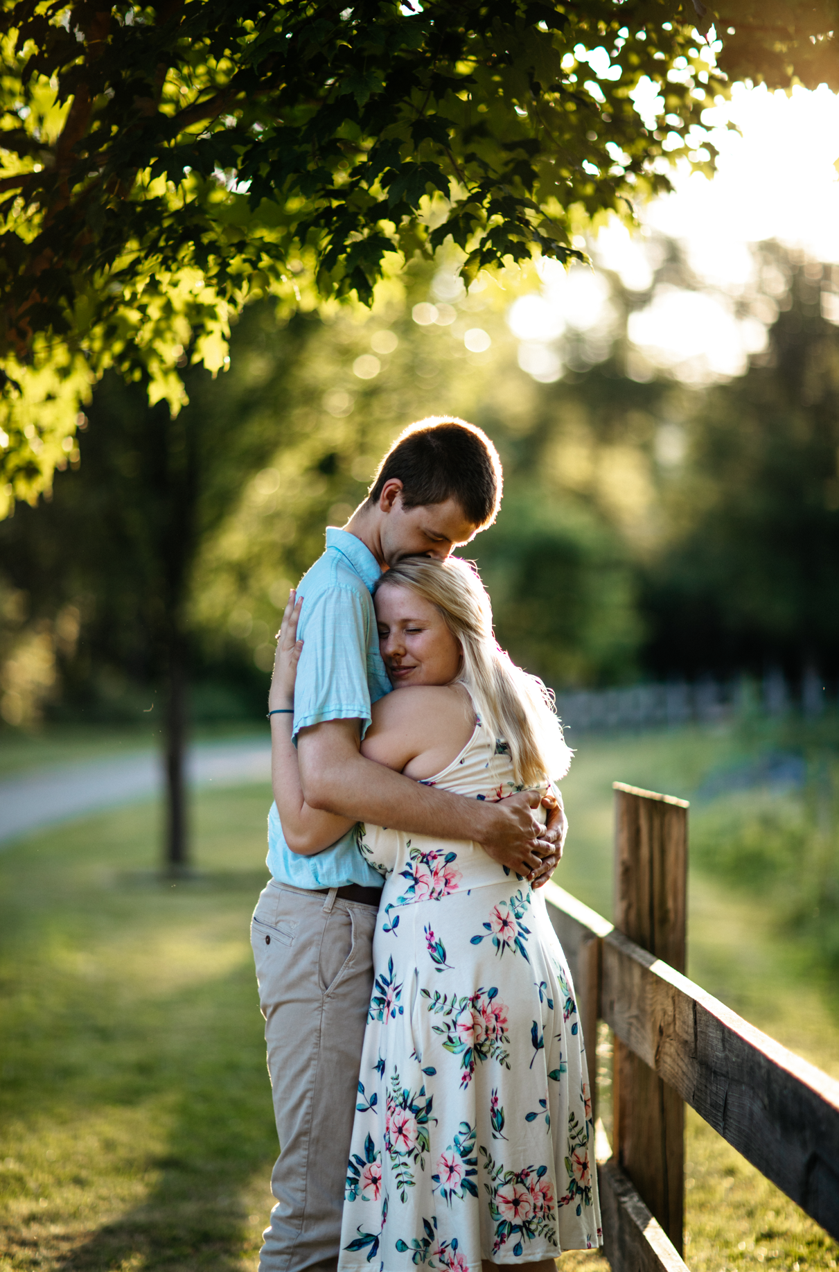 Sweet embrace between couple next to fence along park path Sidney NY