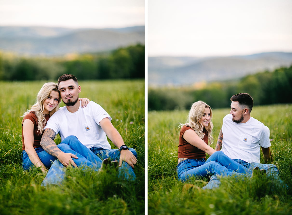 couple sits in grass in field overlooking hills