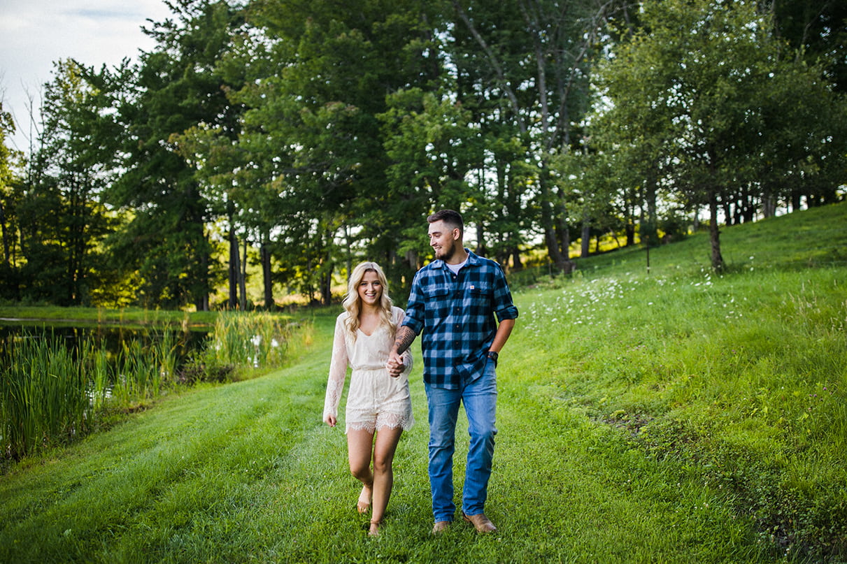 couple holding hands and walking next to pond