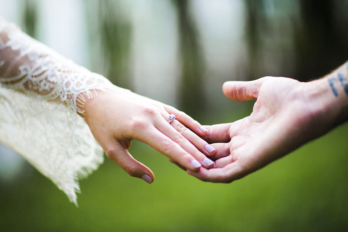 couples hands touching wearing diamond halo engagement ring