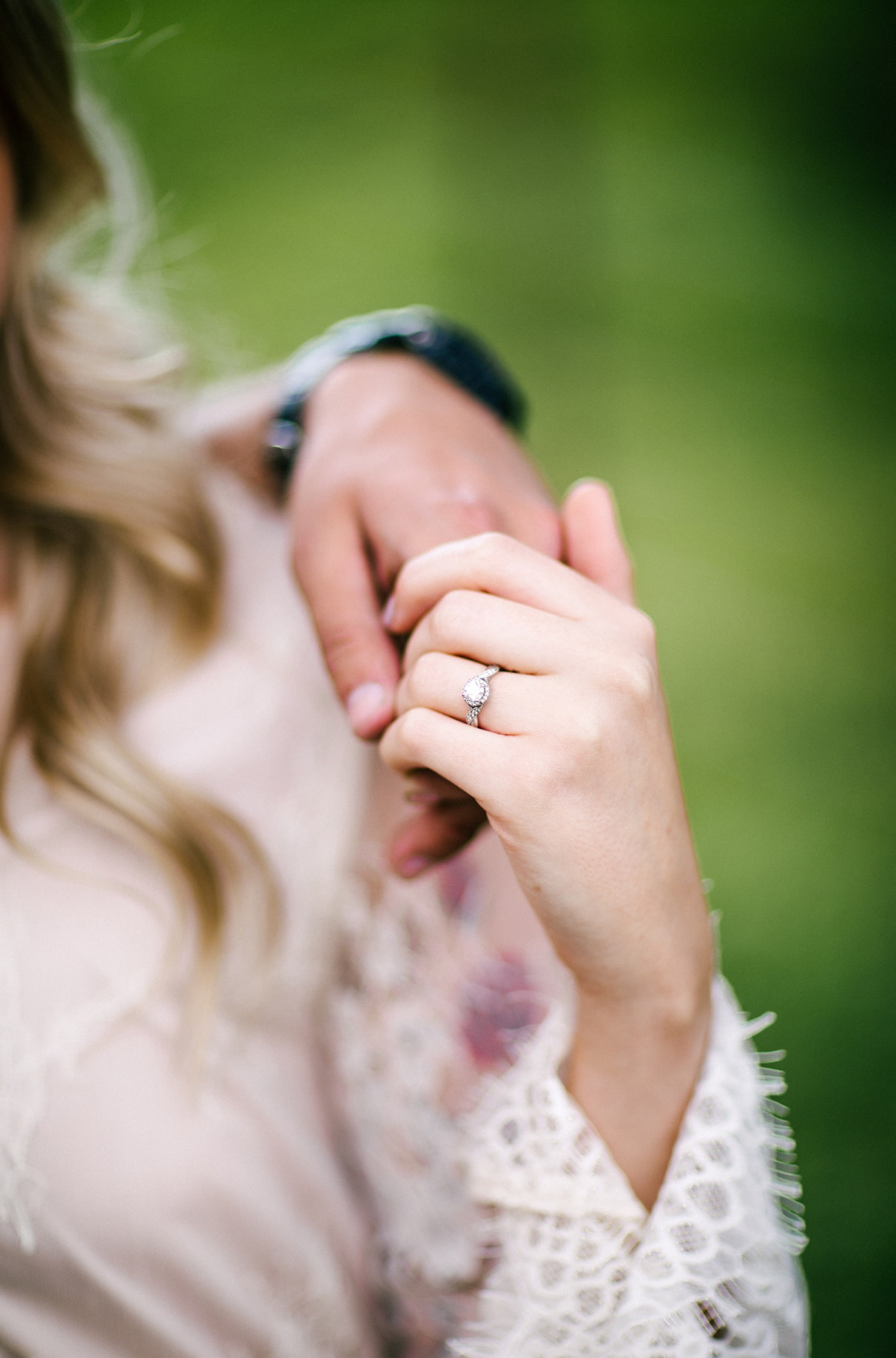 woman with lace sleeves and diamond engagement ring holds mans hand 