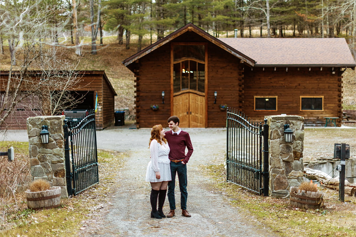 Couple stands in front of iron gate entrance to Glen Park Vineyards in Owego NY
