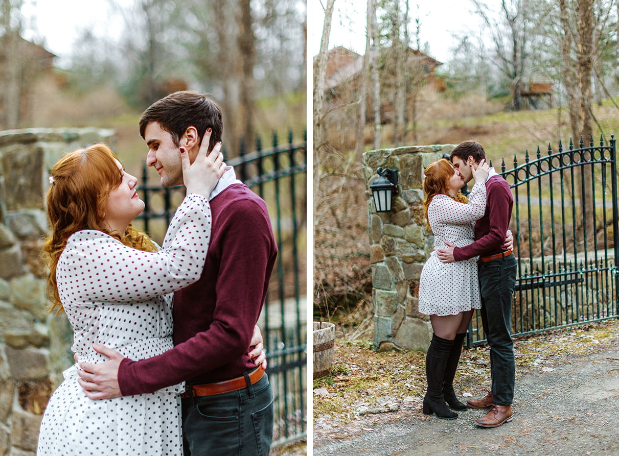 engaged couple kisses in front of a stone and iron fence