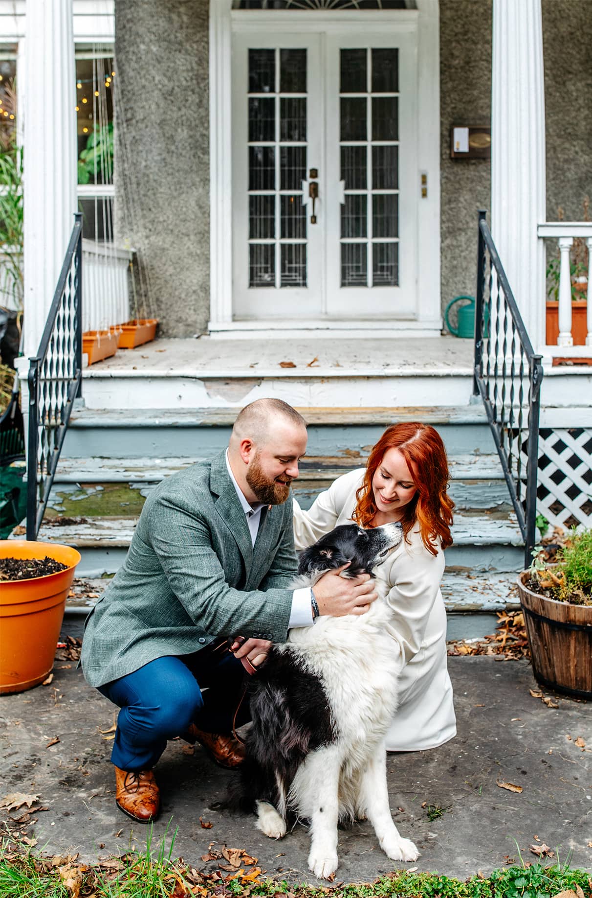 Bride and groom kneel down and pet black and white border collie dog