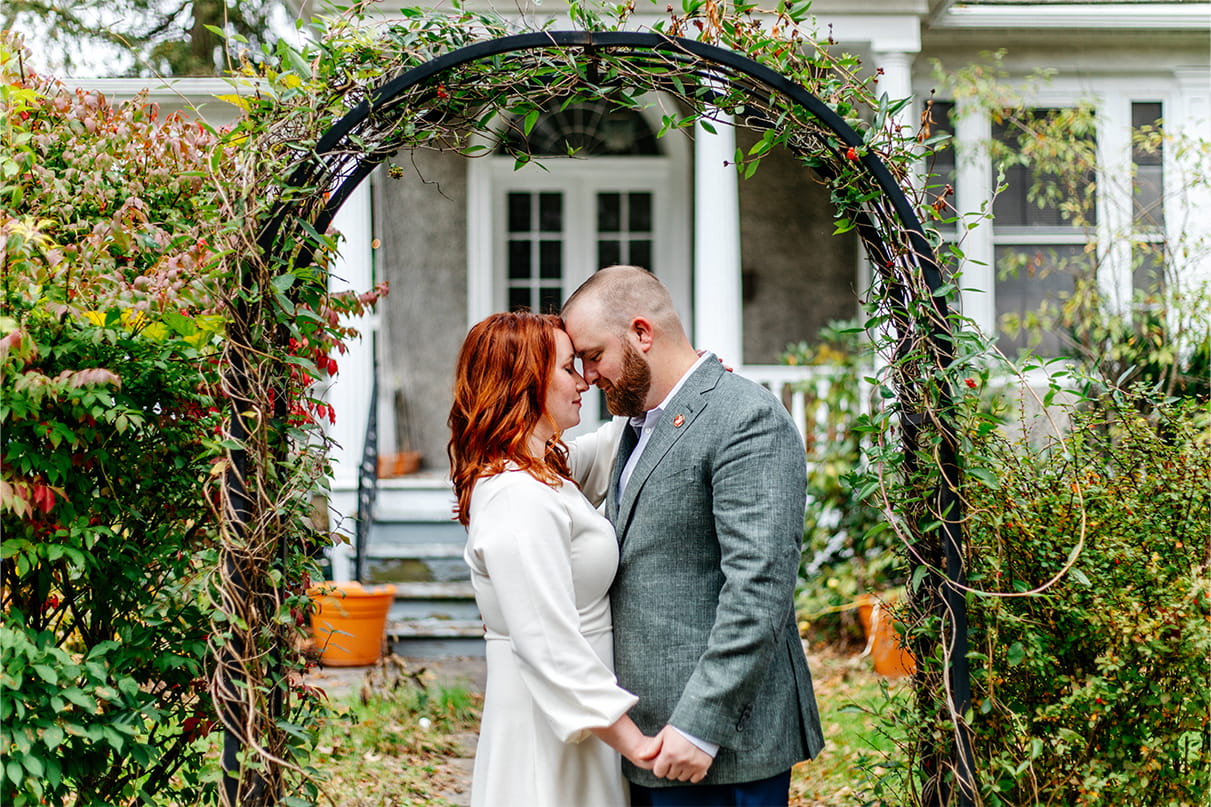 bride and groom stand under vine covered arch