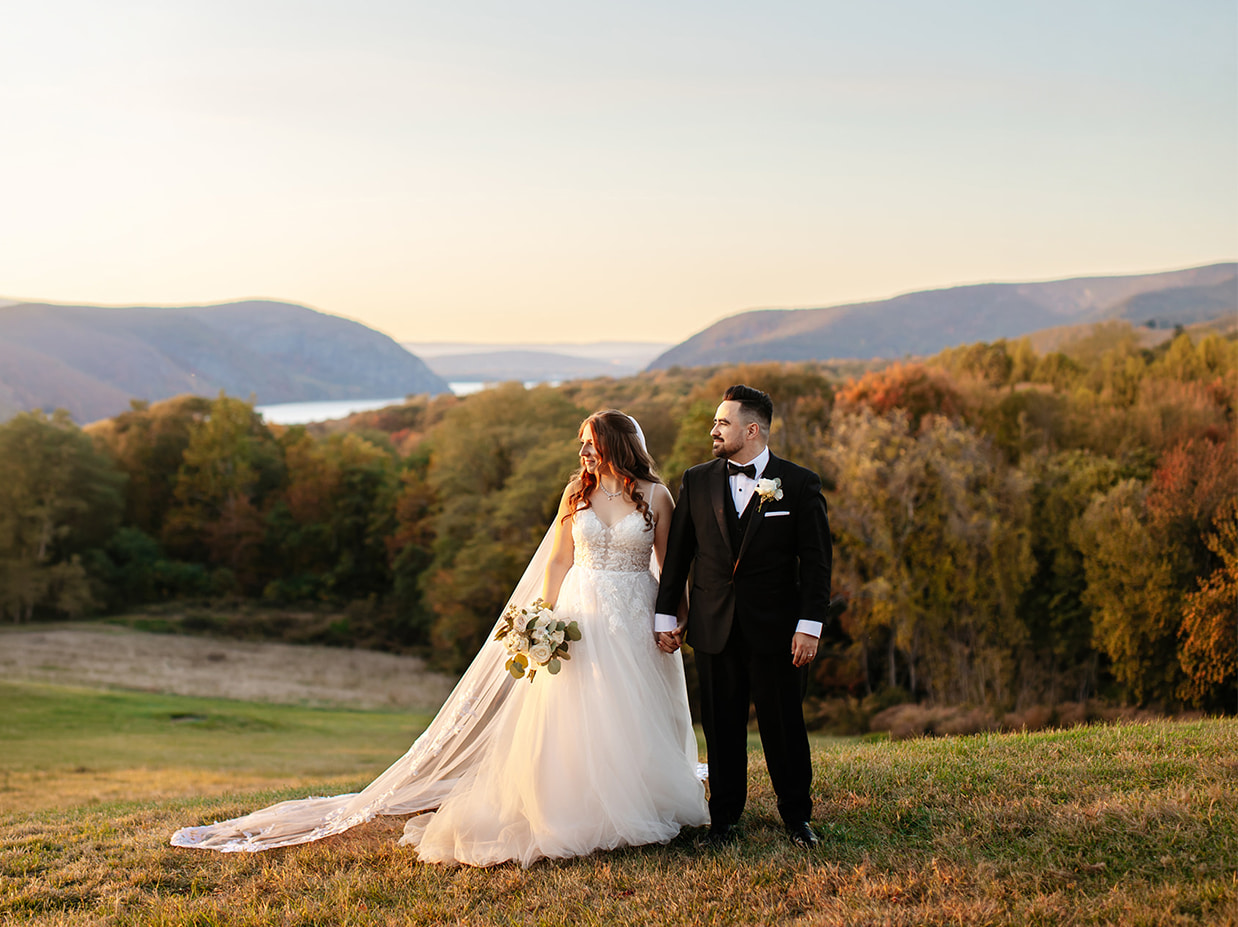 Couple holding hands during a Hudson Valley wedding portrait at golden hour overlooking the mountains and river