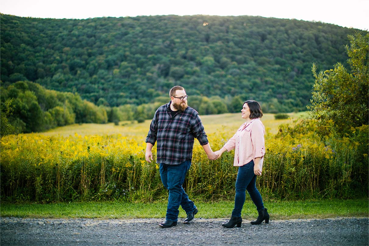 couple walks while holding hands at labrador pond in tully ny